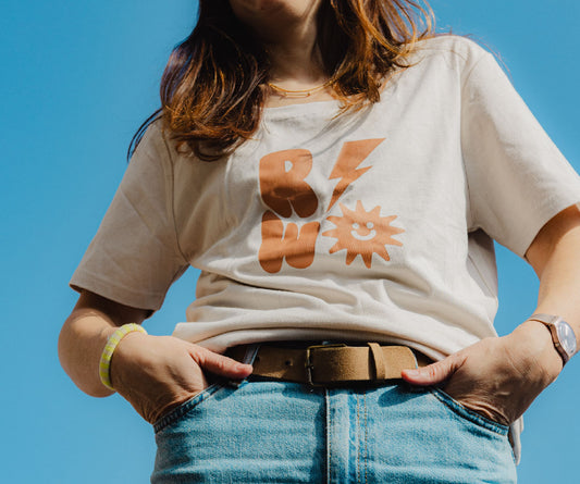 Person wearing a white t-shirt with orange graphics against a clear blue sky