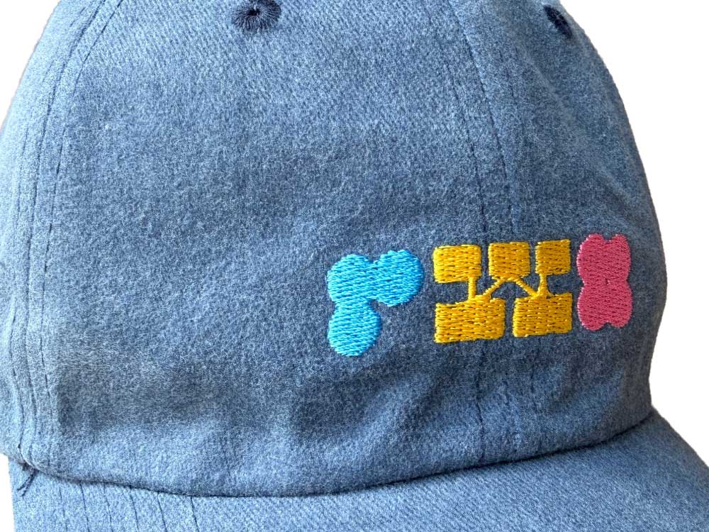 Blue denim cap with colorful embroidered text on a white background